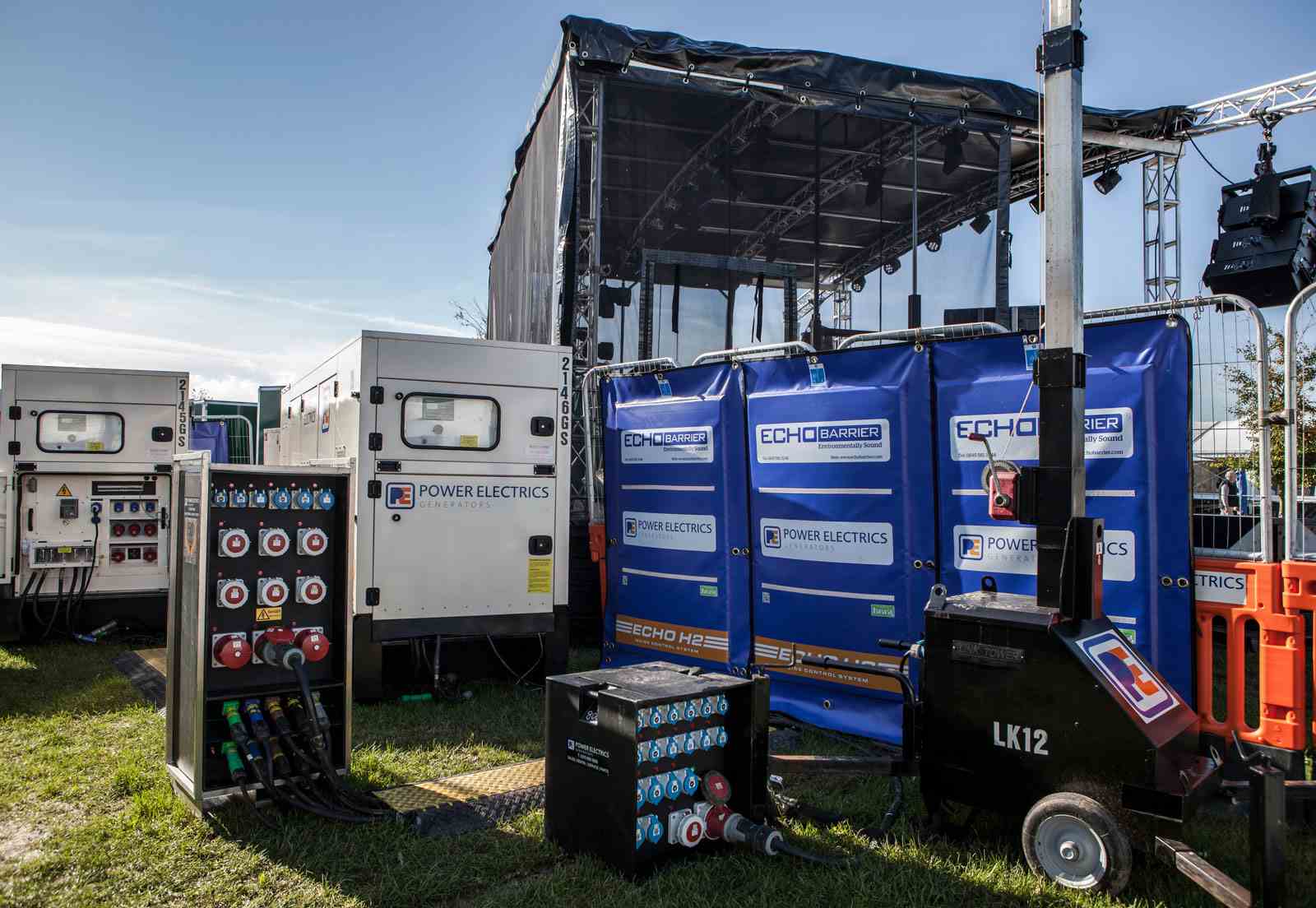 Generators, tower light and switch boards behind music festival stage 